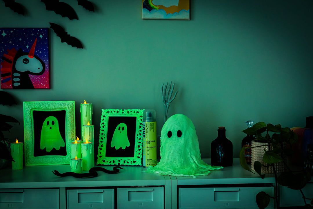 Glowing Halloween decor including frames and cheesecloth ghost on a side table