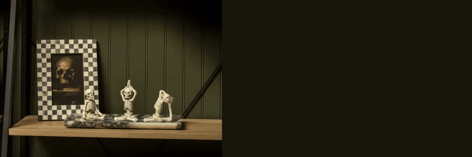 Decorative items on a wooden shelf against a dark green wall