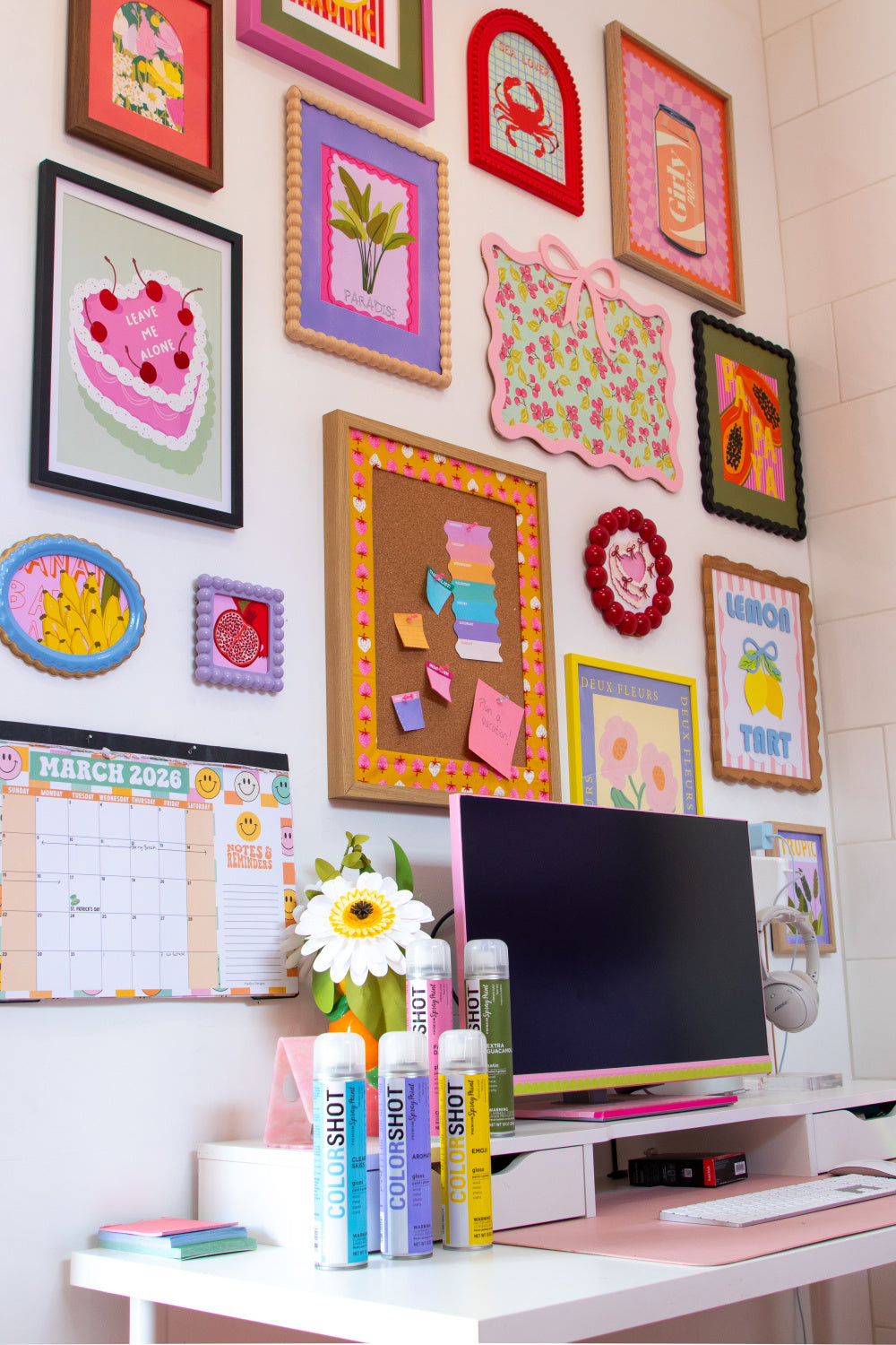 White wall decorated with several framed artwork images with various colored frames and mats. 