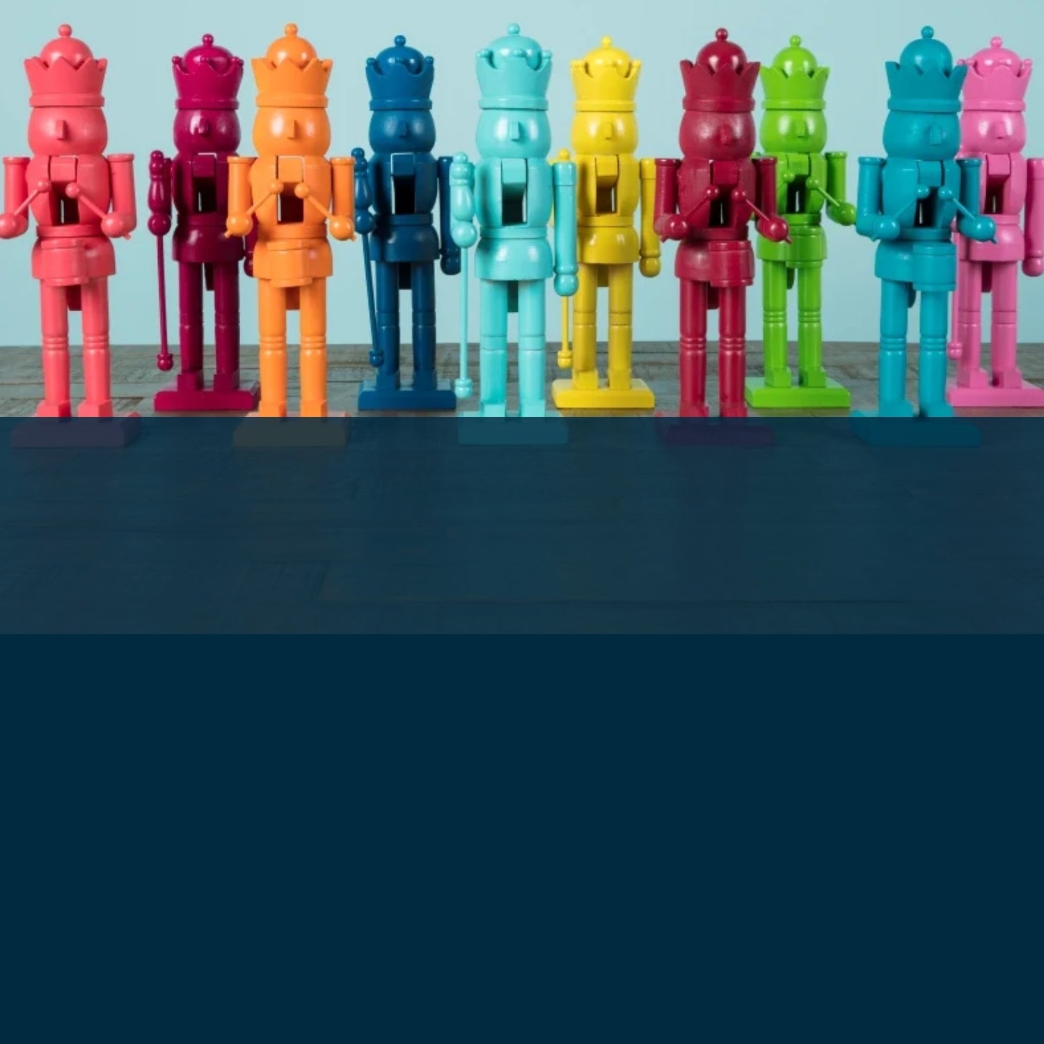 Colorful toy soldiers arranged in a row on a dark surface with a light blue background